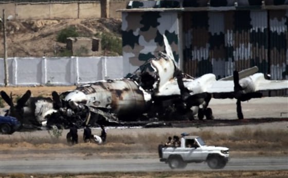 Pakistani troops drive past a wreckage of a gutted aircraft destroyed by militant attacks at a Pakistan Navy base in Karachi, Pakistan, on May 23. Facing a surge in violence after the killing of Osama bin Laden, Pakistanis are taking comfort in conspiracies theories that allege Indian or American agents — not fellow Muslim countrymen — are behind the attacks.